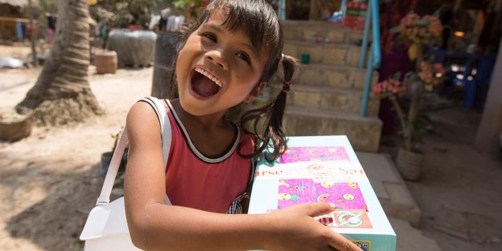 Young girl smiles with shoebox and handbag