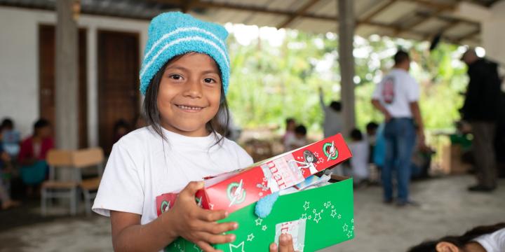 child in hat smiling with shoebox gift