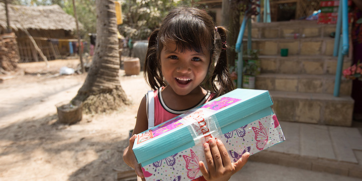 Girl in Cambodia smiles holding shoebox