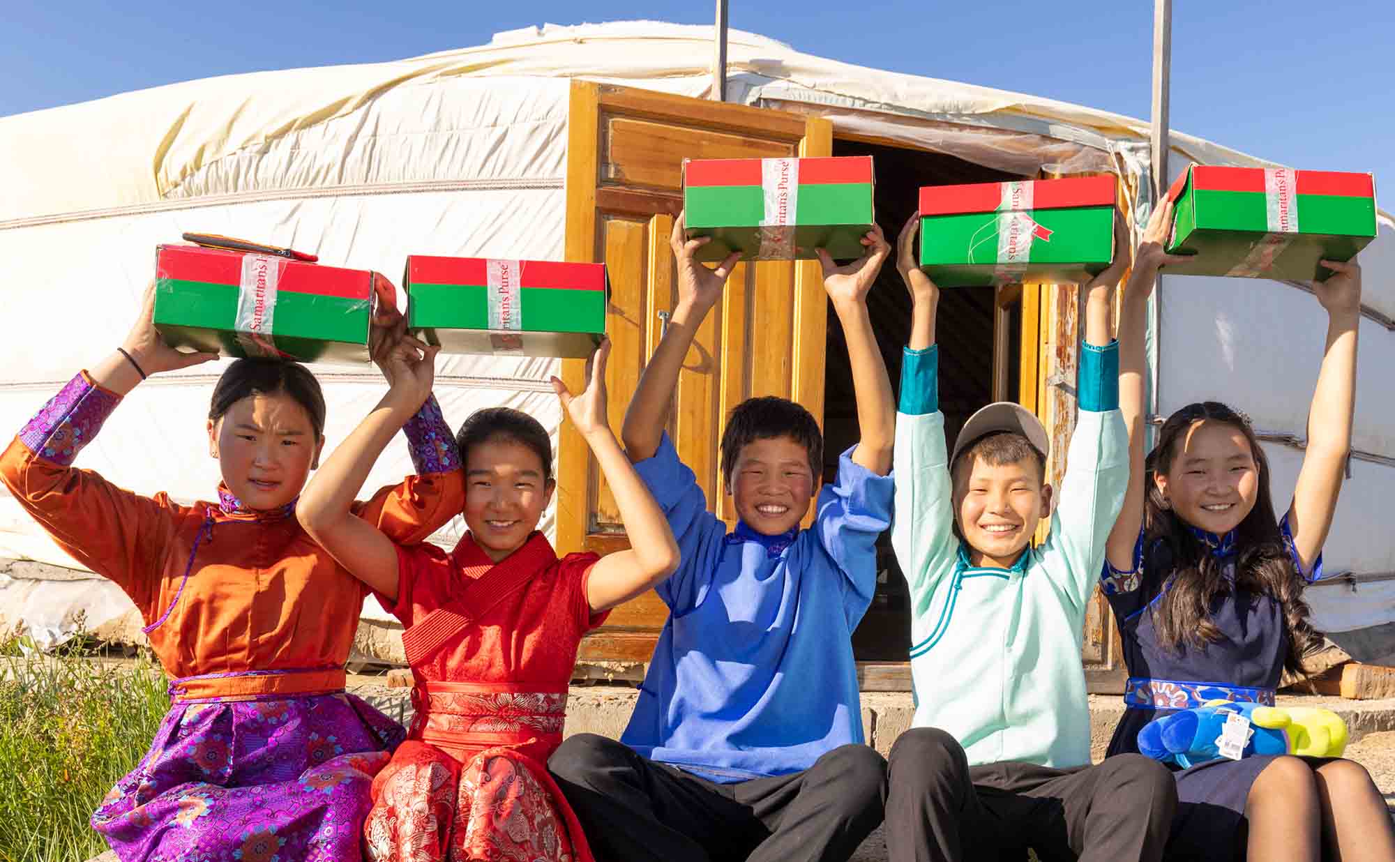 Group of children holding shoebox gifts high