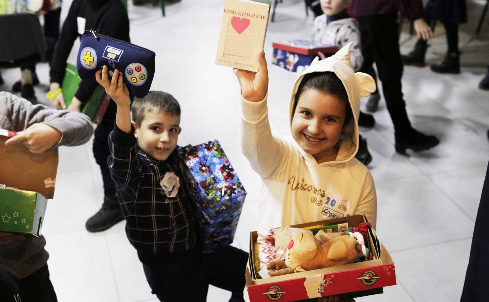 Smiling children showing shoebox gifts