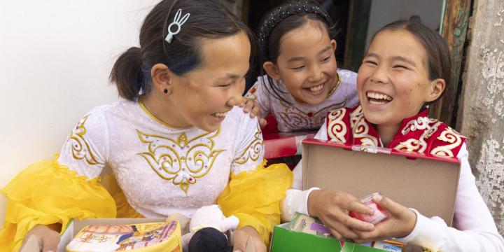 Girls smiling as they explore shoebox gifts