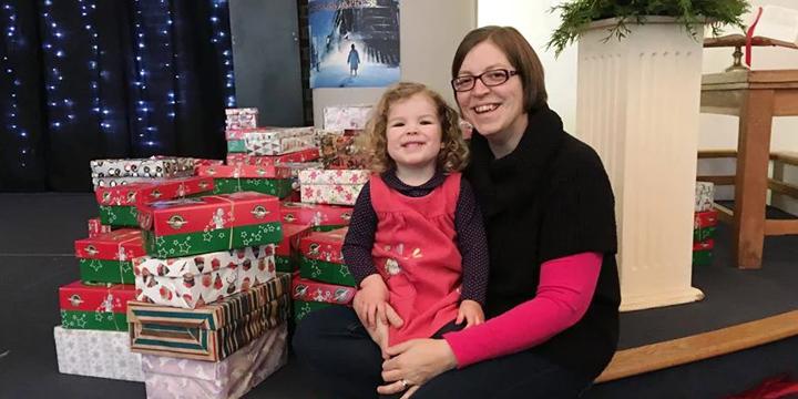 Mother and daughter by pile of shoebox gifts