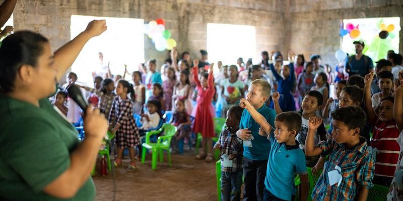 Loida Varela leads the local children in a praise song at the outreach event.