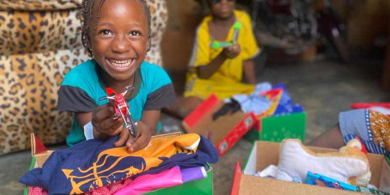 child grinning sitting with shoebox