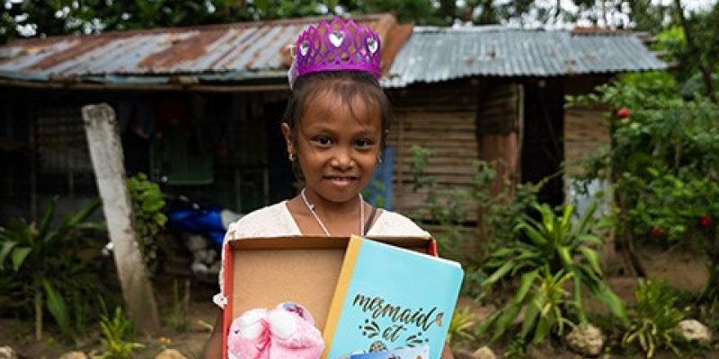 little girl wearing tiara and holding shoebox