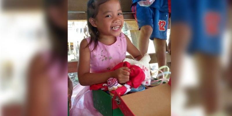 A girl enjoys discovering all the treasures inside her Operation Christmas Child shoebox gift.