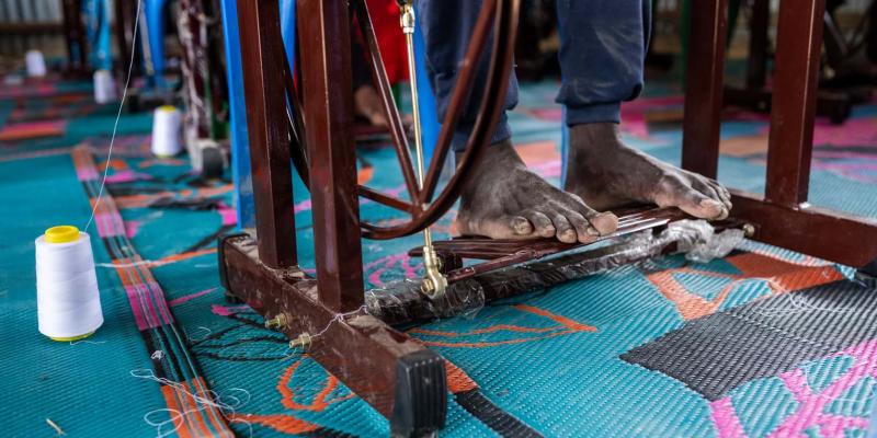 His feet carried him away from years of danger. Now they power his sewing machine as he works toward a new life one stitch at a time.