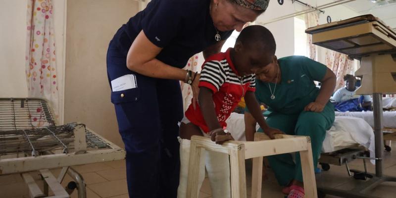 Tracy-Lynn Schuster, a physical therapist on the orthopaedic team, helps Abraham walk after his successful surgery.