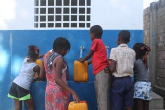 Children fill plastic containers with water from one of the water points we’ve constructed in Haiti.