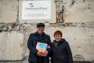 The Ukrainian farming couple stand in front of their newly restored grain storehouse.