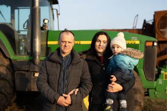 Displaying their spirit of resilience, Oleksiy and his wife pose in front of their tractor with one of their three children.