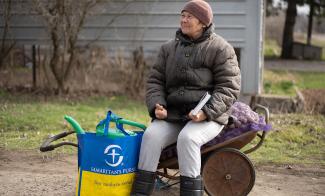 A Ukrainian woman clutches the Bible she received along with seed potatoes and other gardening supplies from Samaritan’s Purse.