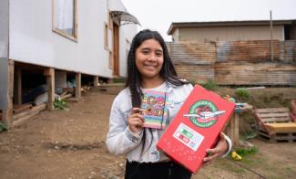 The school supplies Fernanda found in her shoebox gift showed her God’s love in the wake of the fire her family had experienced. She is also grateful for her new home that is behind her on the left.
