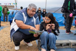 Pastor Sixto unpacks The Greatest Gift Gospel booklet for one of the children at an Operation Christmas Child outreach event.
