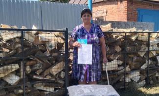 Anna, a stroke survivor, is grateful for the load of firewood from Samaritan’s Purse that will help her survive Ukraine’s winter. She proudly displays the Bible in her language that she received along with the fuel.