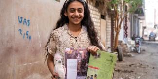 A young girl in the Middle East holds a copy of The Greatest Journey discipleship booklet.