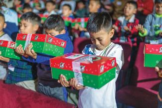 CHILDREN pray to the Lord before opening their gifts.