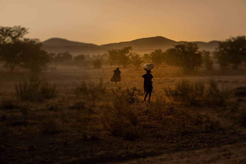Himba women walking across a dusty plain